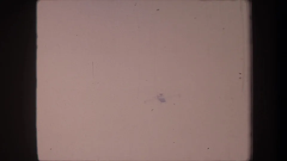 Aircraft reduced to a small dark speck in the lower-center of the faded 8mm frame as the clip ends, circa 1959 California.