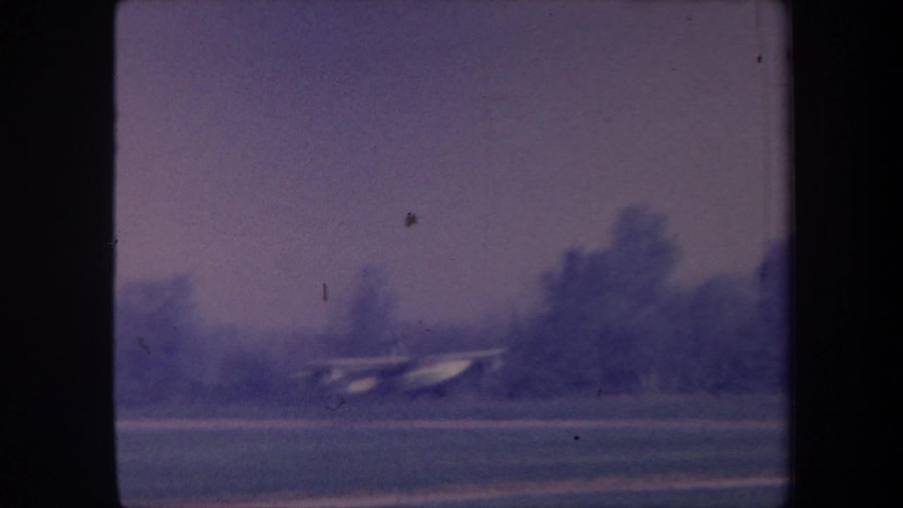Small seaplane on a grass airstrip, possibly Yucaipa, California, circa 1959; 8mm home-movie footage with characteristic blue-purple color drift.