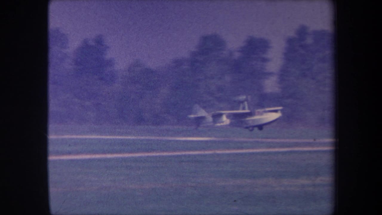 Seaplane accelerating or decelerating on a grass strip, likely Yucaipa, California, circa 1959; motion blur and 8mm grain evident.