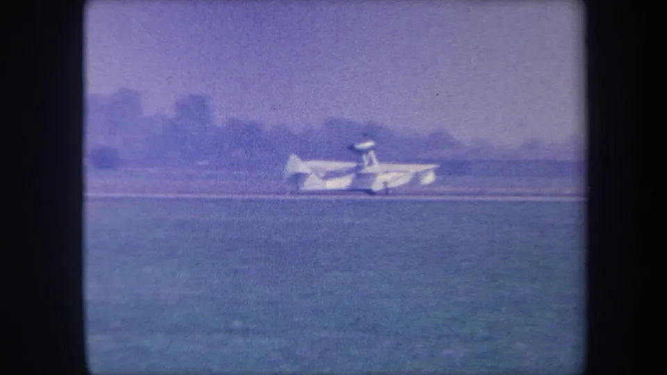 Small amphibious aircraft taxiing further away across a grass airfield, likely Yucaipa, California, circa 1959; heavy blue-purple color shift visible.
