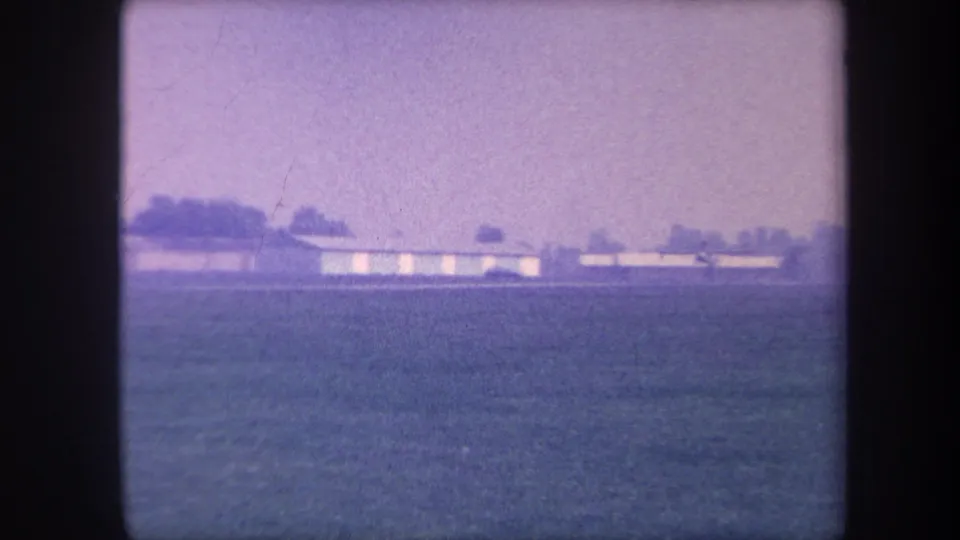 Closing 8mm frame of a circa 1959 Yucaipa airfield sequence; hangar on the distant horizon with the field stretching across the foreground.