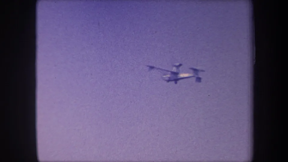 Light aircraft now smaller and further from camera against purple-shifted sky, final seconds of 8mm home movie, circa 1959, Yucaipa, California.