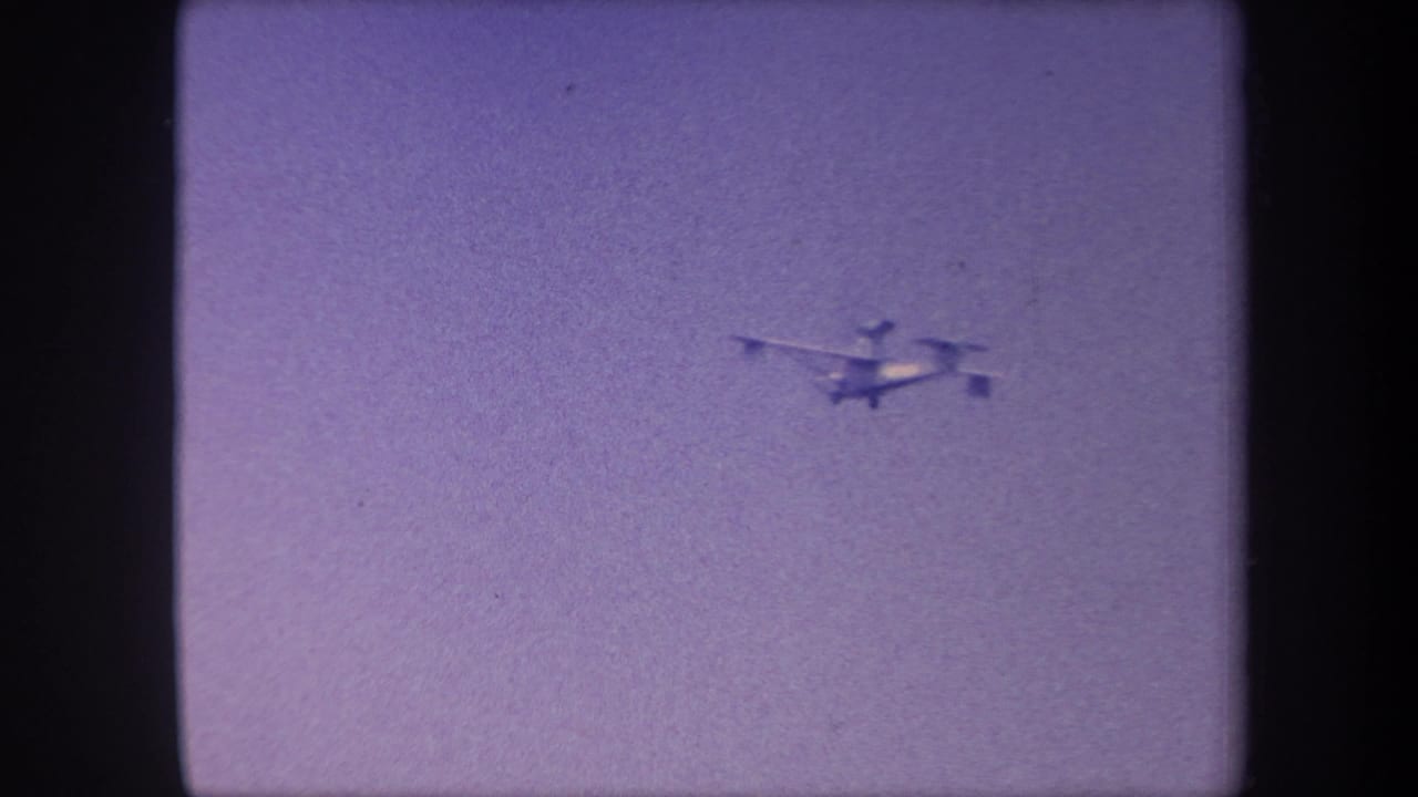 Propeller aircraft tracked mid-flight against an overcast lavender sky in this 1959 California 8mm home movie; aircraft appears closest in this opening frame.