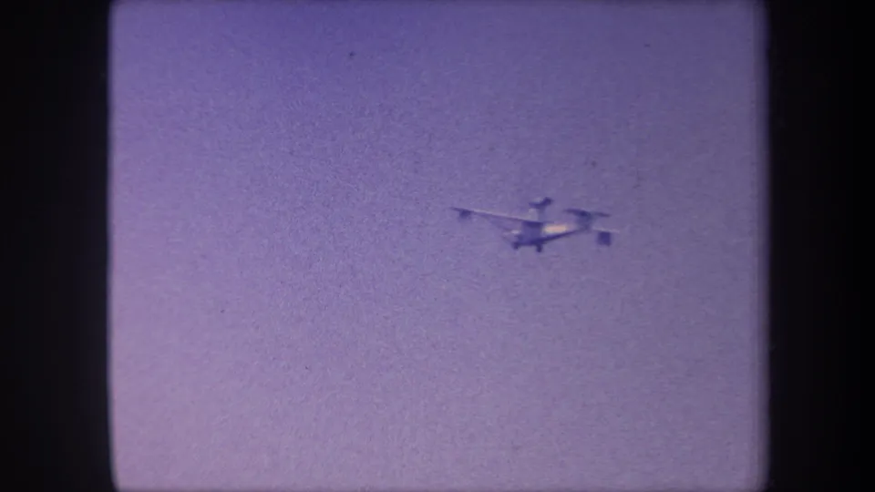 Propeller aircraft tracked mid-flight against an overcast lavender sky in this 1959 California 8mm home movie; aircraft appears closest in this opening frame.