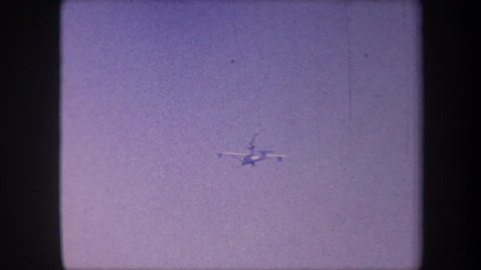 Propeller aircraft tracked to lower-left; 8mm grain and light film scratches mark the aged 1959 stock from this Yucaipa, California home movie.