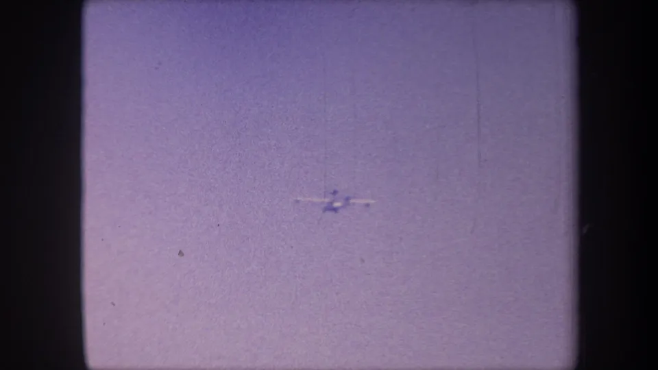 The aircraft near the lower-right edge as the clip concludes, still against the featureless lavender overcast sky of this 1959 California 8mm reel.