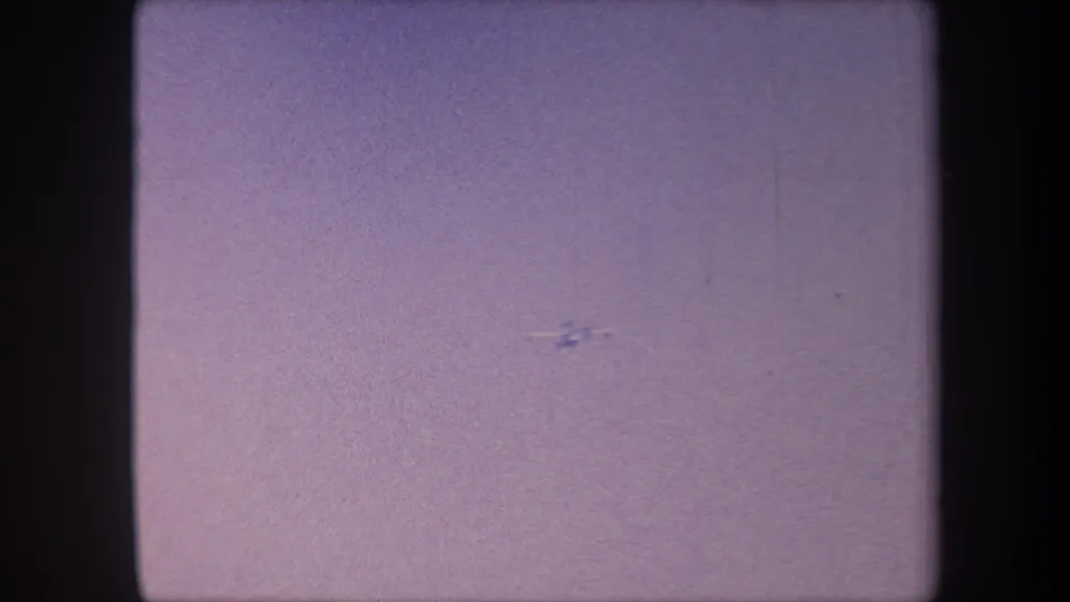 Small aircraft descending or banking to a lower position in 8mm home movie footage attributed to Yucaipa, California, circa 1959.