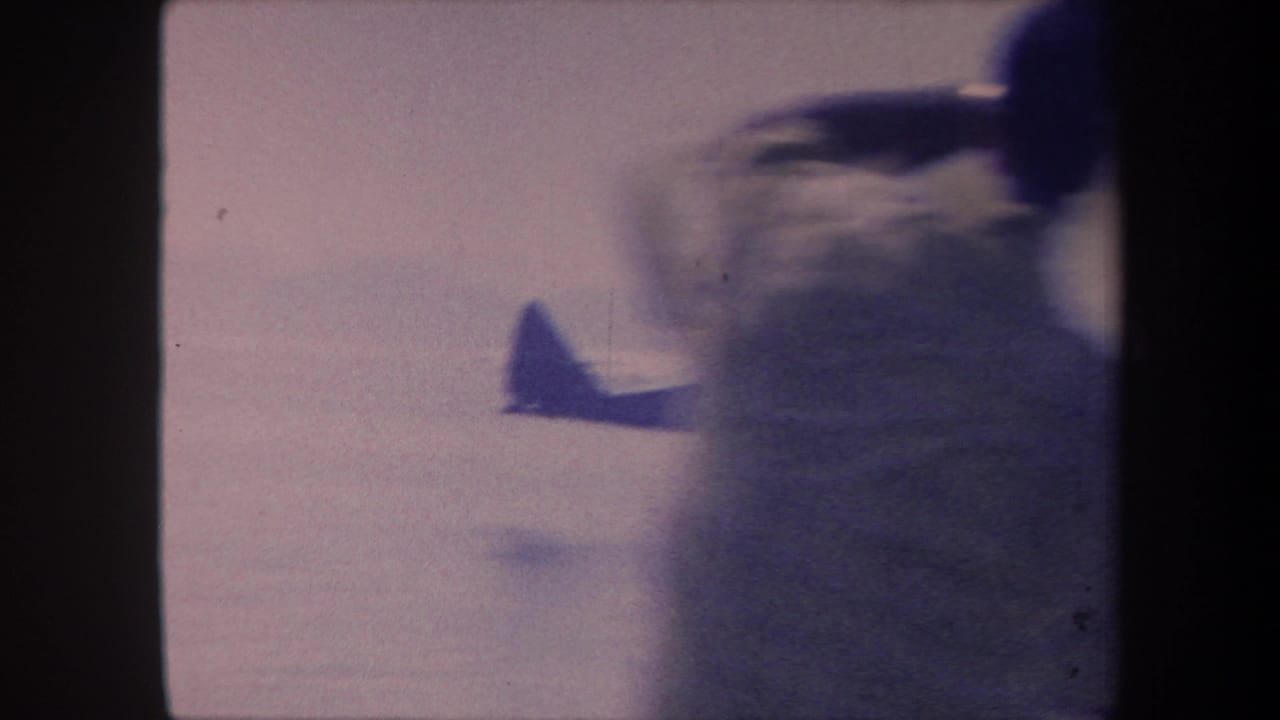 Camera pan during seaplane approach creates heavy motion blur; blurred figure partially visible at frame edge, 1959 California 8mm