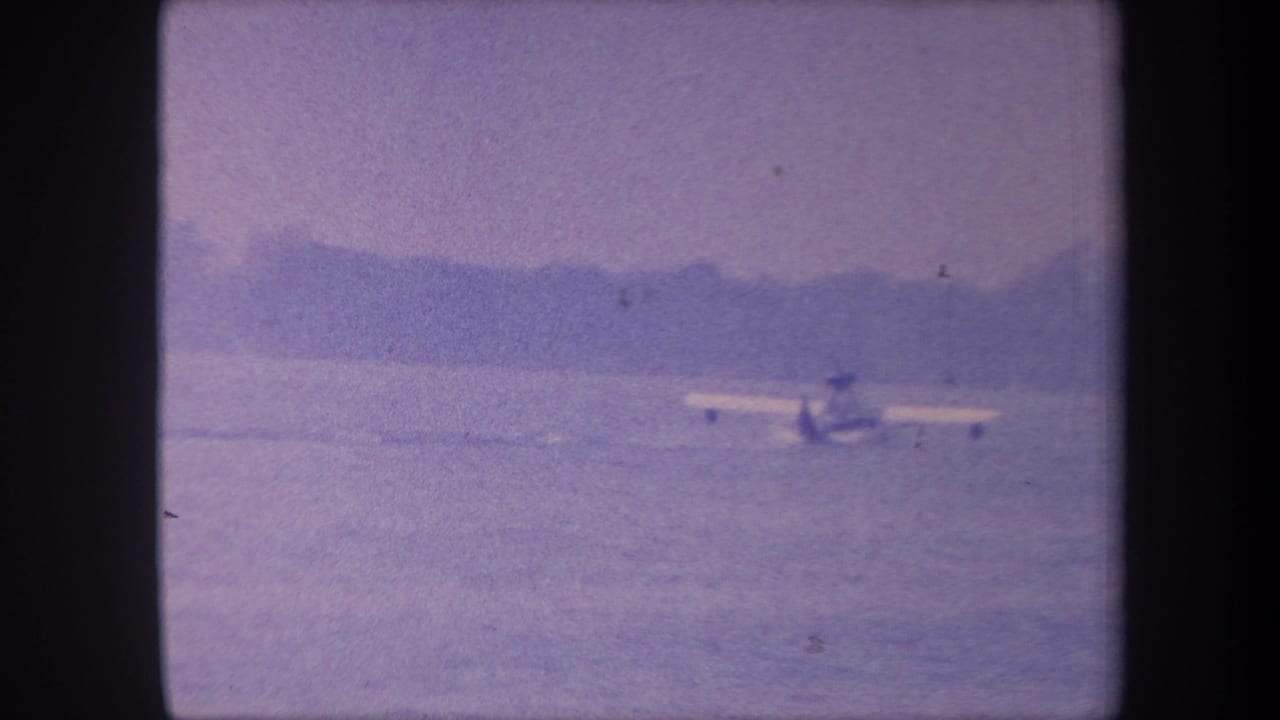 Amphibious aircraft on calm water with distant hills, 8mm color-reversal footage consistent with late-1950s southern California