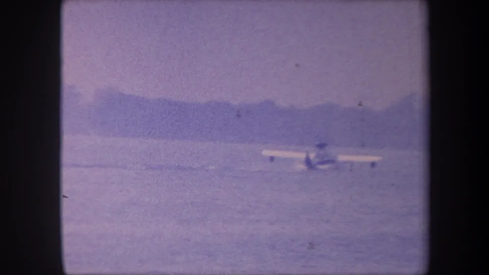 Amphibious aircraft on calm water with distant hills, 8mm color-reversal footage consistent with late-1950s southern California