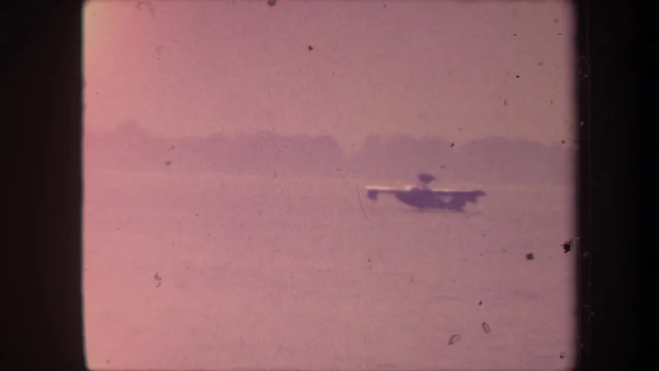 Small seaplane approaching or touching down on a calm California lake, recorded in faded 8mm home-movie footage circa 1959.