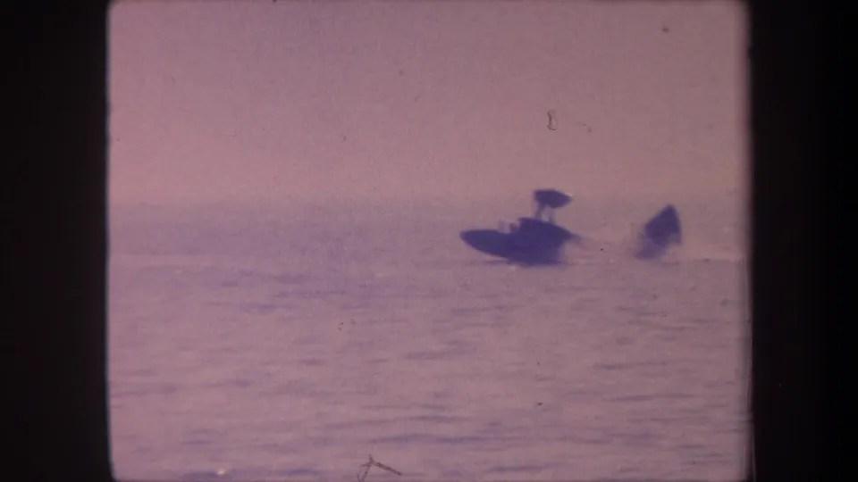 Aquaplane small in frame on open lake, late-1950s 8mm home movie footage, strong pink-lavender dye shift and visible grain