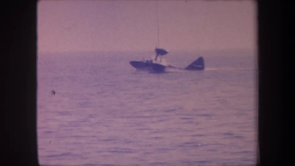 Small single-engine seaplane with pontoon floats on open water, 8mm home-movie footage, possibly California circa 1959