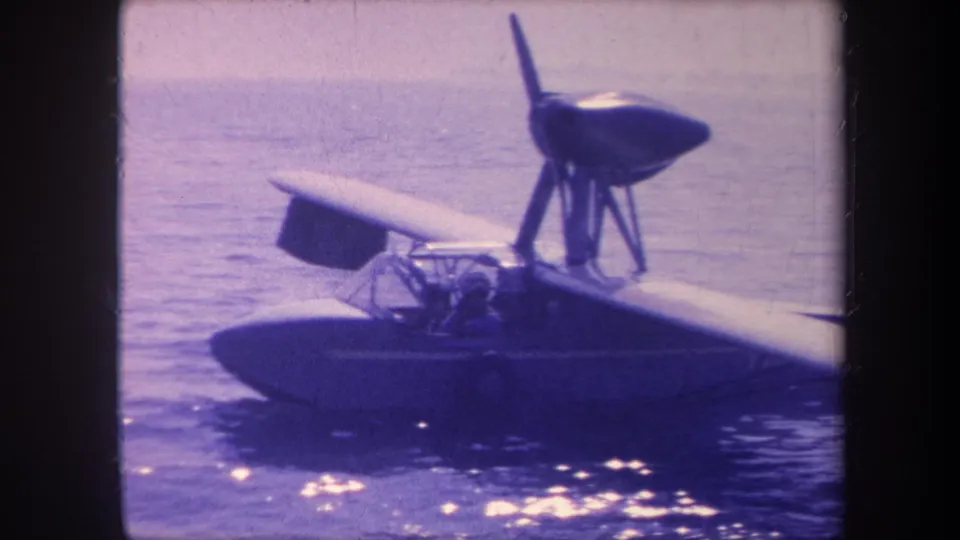 8mm home-movie frame, c. 1959, showing a single-engine flying boat at rest on open water in California.