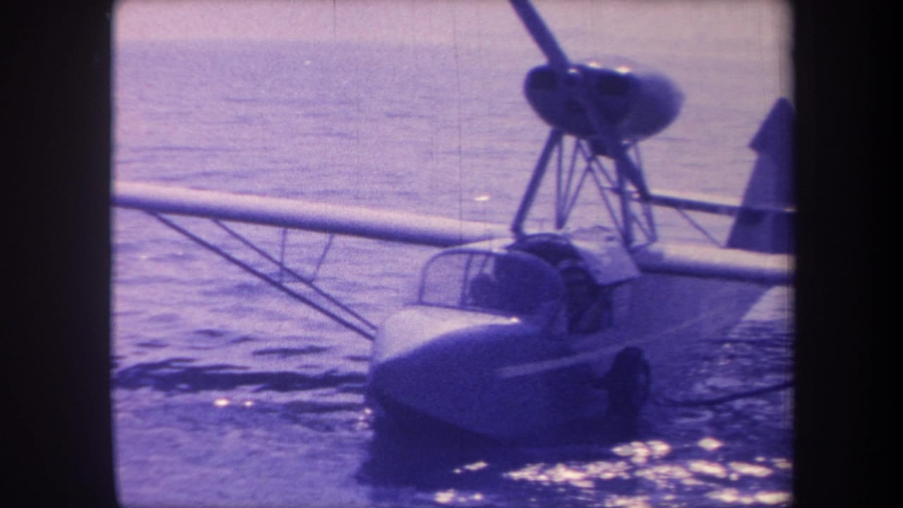 Mid-century seaplane hull and propeller at close range on calm open water, circa 1959; 8mm home movie with pronounced blue-purple dye fading and visible strut bracing.
