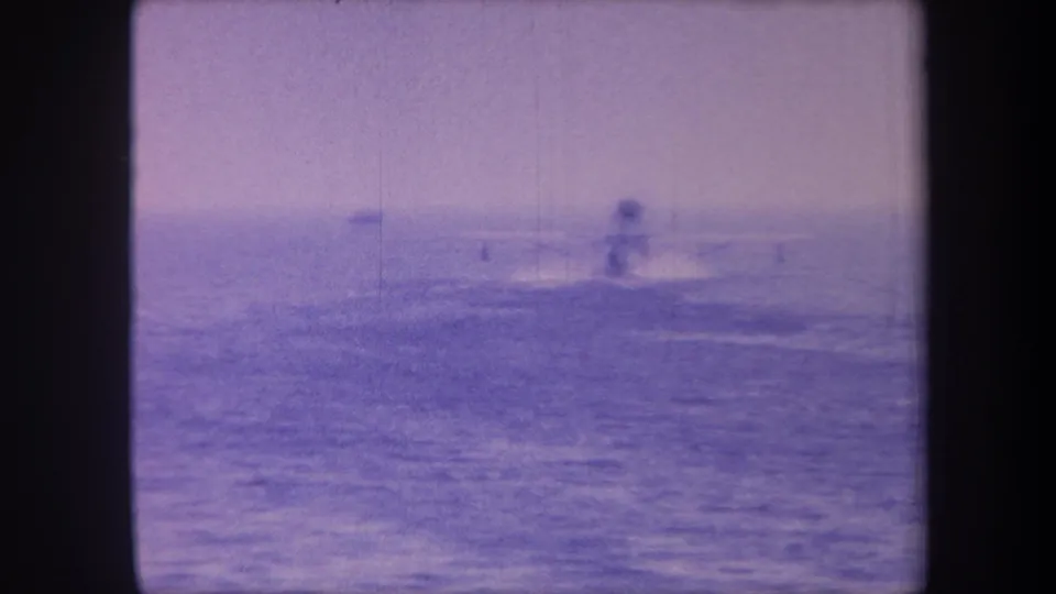 Seaplane taxiing on open ocean with faint small distant object, 1959 California home movie with aged purple 8mm color cast.