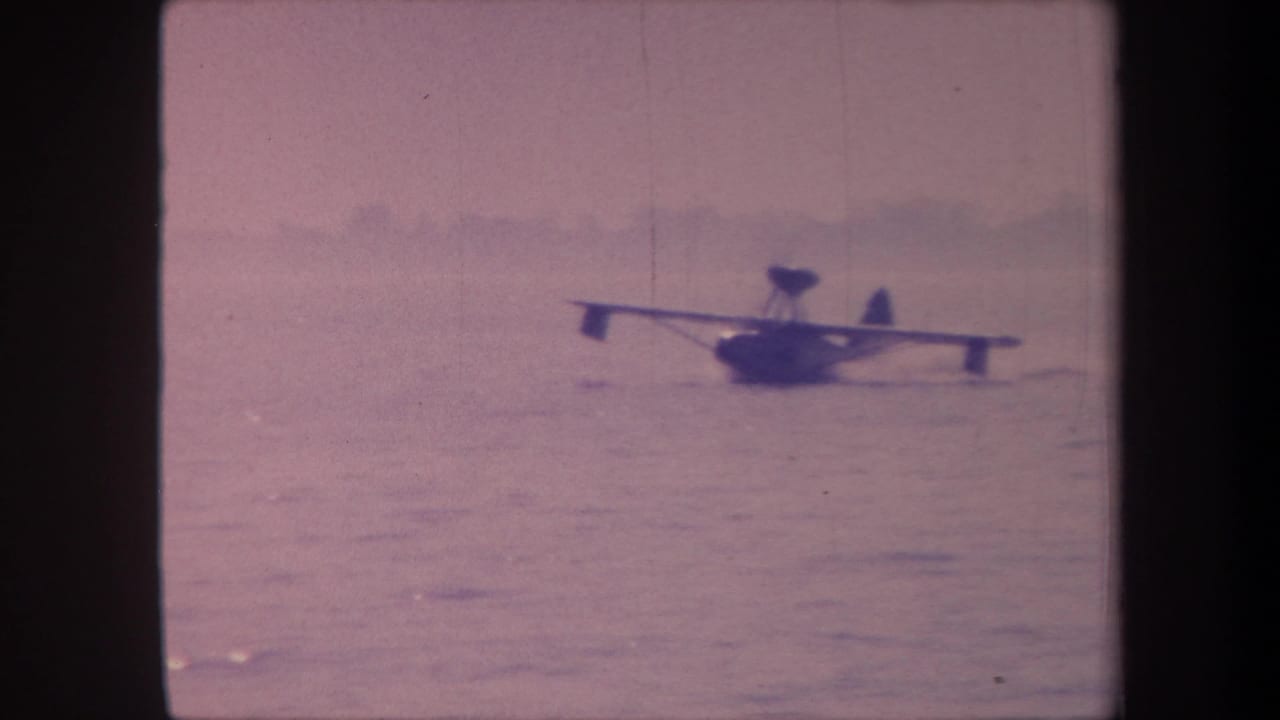 Floatplane or flying boat on open water, possibly California c.1959 per metadata, shot on aged 8mm color film with characteristic lavender cast.