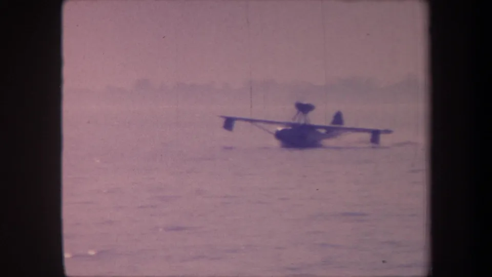 Floatplane or flying boat on open water, possibly California c.1959 per metadata, shot on aged 8mm color film with characteristic lavender cast.