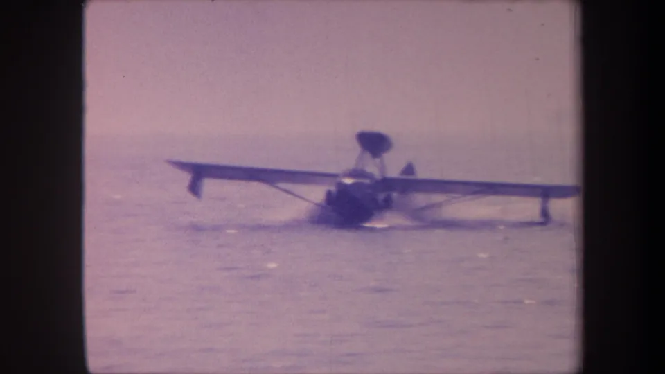 Amphibious aircraft maneuvering on open water, possibly during a takeoff run, c.1959, aged 8mm color stock with lavender cast.