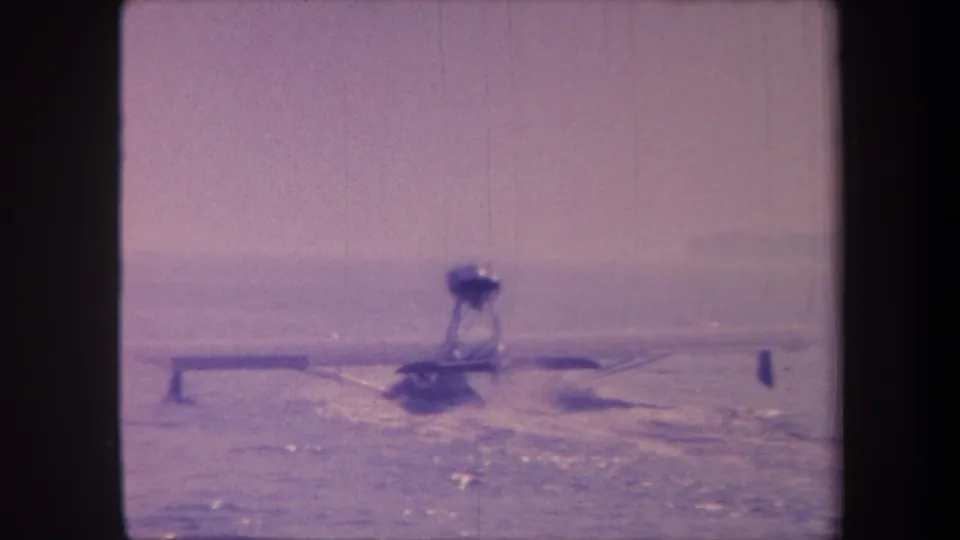 A propeller floatplane continues across open water in California, circa 1959, with characteristic purple dye shift of aged 8mm reversal stock.