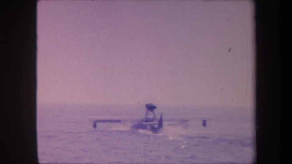 Floatplane during water takeoff run in 1959 8mm home movie, aircraft appears further from camera, purple-lavender color-shifted film stock.