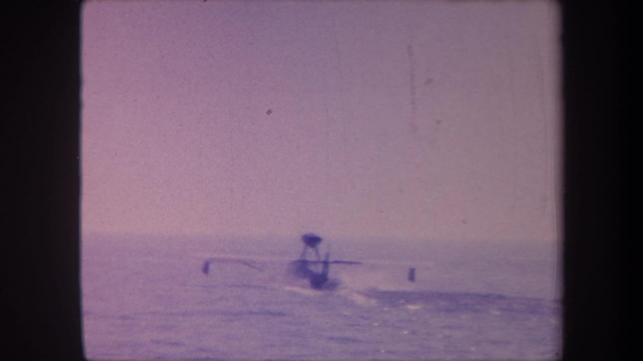 1950s 8mm home movie frame showing a hydroplane boat silhouette on open water, attributed to Yucaipa California, with heavy purple dye cast from aged film.
