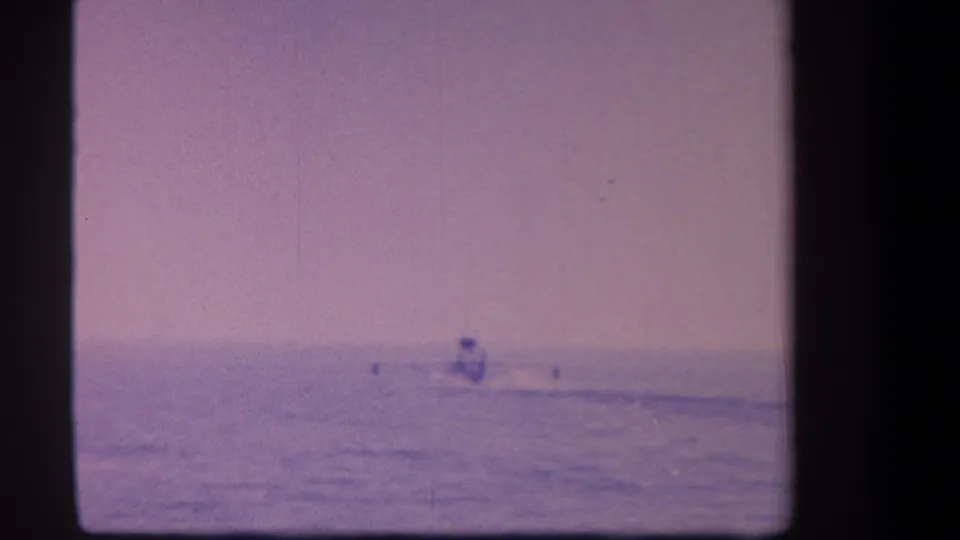 Surfer in the mid-distance on open water, 8mm film with heavy purple dye cast and grain, circa 1959 California.