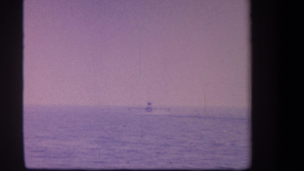 Distant plane crossing the horizon above calm open water.
