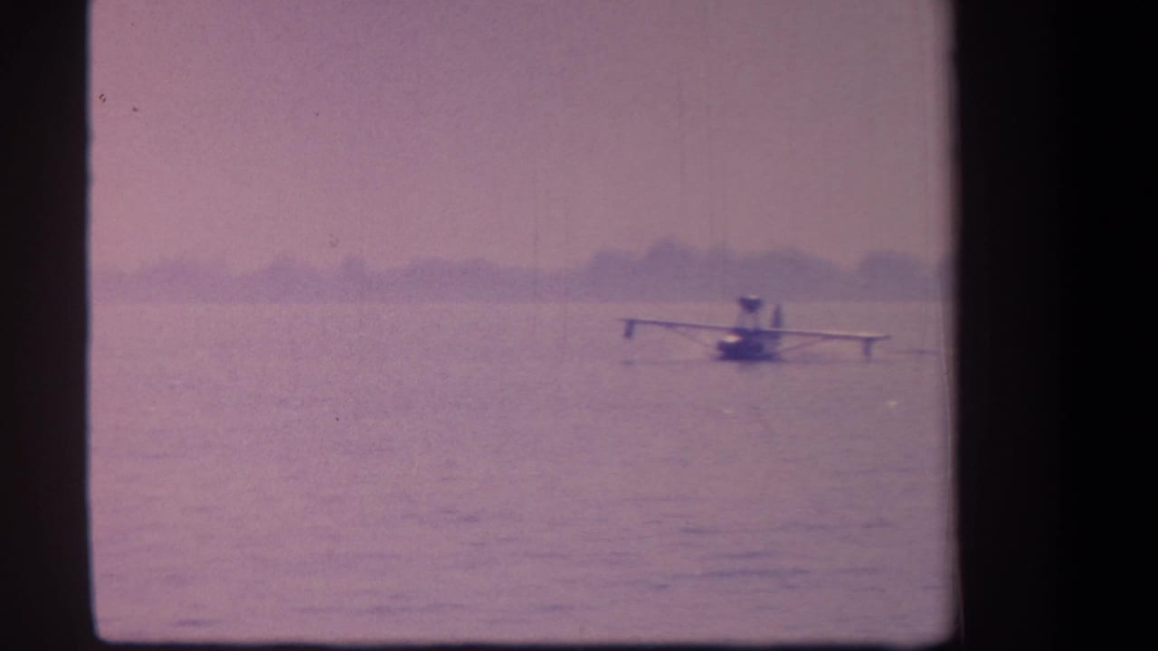 Small floatplane farther right on the water beneath a hazy sky.