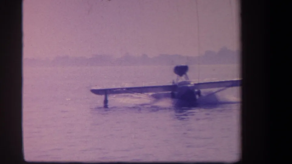 Closer 1959 California home-movie frame showing the seaplane partly near the right edge as it floats on the water.