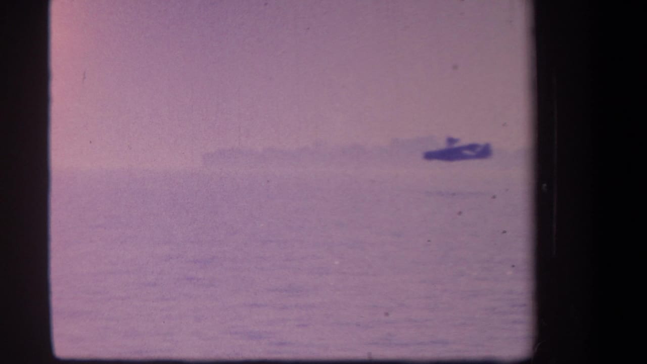 Small hydroplane silhouette on calm water under a faded pink-purple sky.
