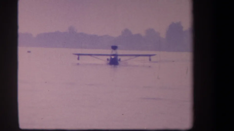 1959 8mm frame showing the floatplane closer and viewed from behind as it moves across the lake at Volmer Yucaipa.