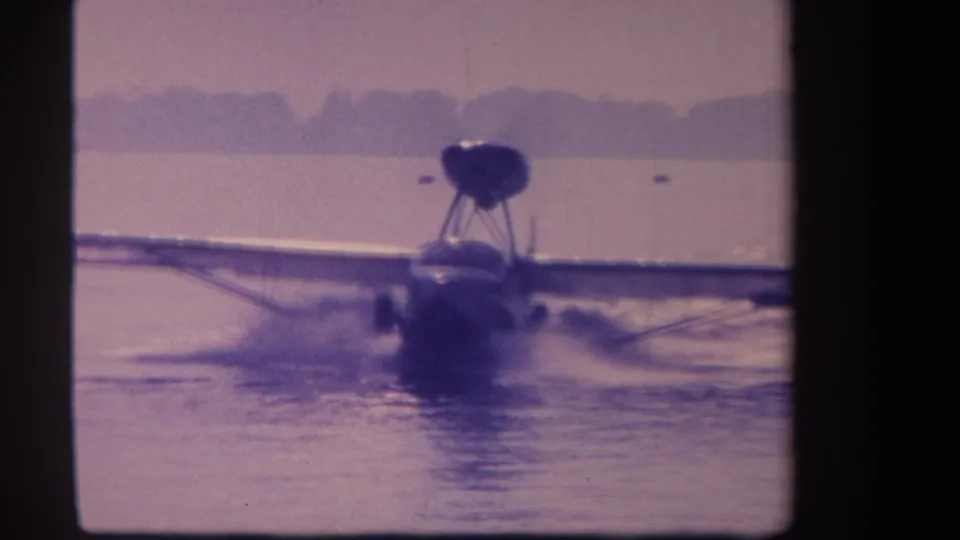 1959 8mm view of a high-wing seaplane nearing the camera as water spray forms around the hull or floats.