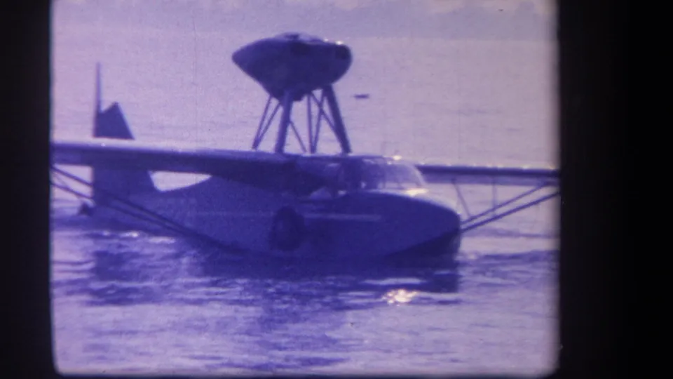 Likely Volmer Yucaipa aircraft on water in 1959 home-movie footage, with wing, cockpit, and elevated propeller assembly visible.
