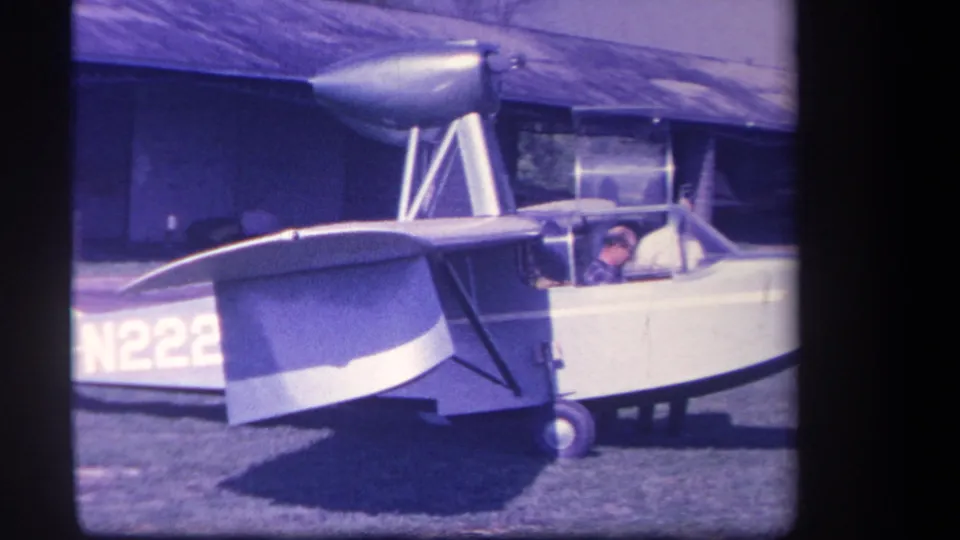 Final 1959 Yucaipa frame showing the amphibious aircraft from the side, with partial N222 registration, landing wheel, and men at the cockpit.