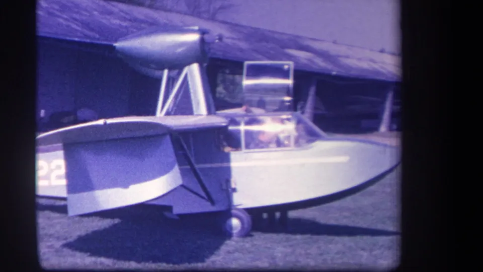 1959 Yucaipa frame of a small amphibious aircraft on grass, with the cockpit canopy and high wing clearly visible.
