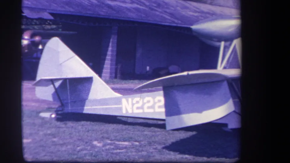 1959 8mm frame showing the aircraft tail, rear fuselage, and visible N222 marking while parked outdoors in Yucaipa, California.