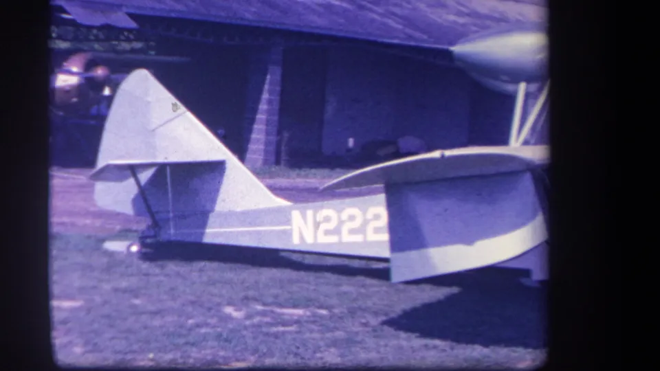 1959 8mm frame of the small aircraft from the rear side, with tail fin, wing, wheel, and partial N222 registration visible.