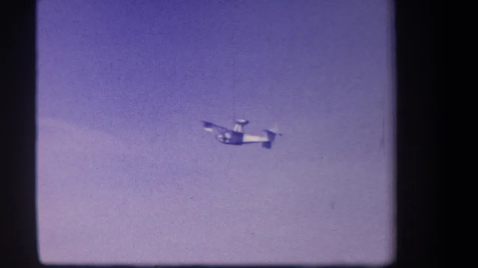 Small propeller plane appears lower against the purple-tinted sky, with a faint cloud band in this 1959 California 8mm frame.