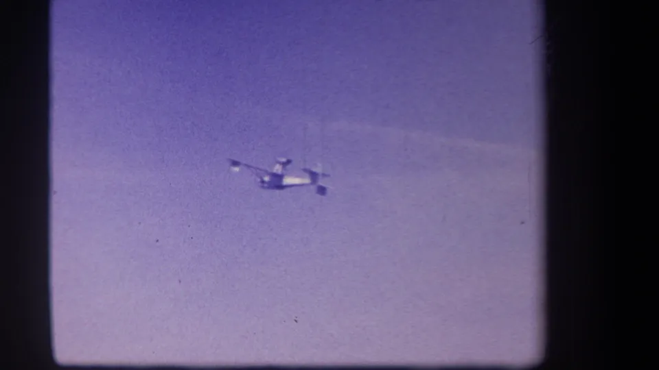 Distant small plane crosses open purple-tinted sky near a faint cloud band in the final 1959 Yucaipa 8mm frame.