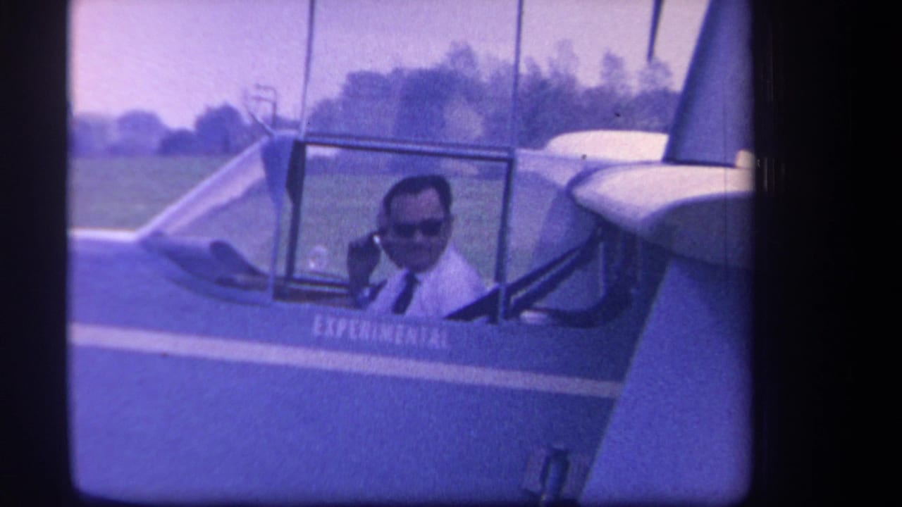 Man in sunglasses seated in an open glider cockpit beside visible EXPERIMENTAL lettering.