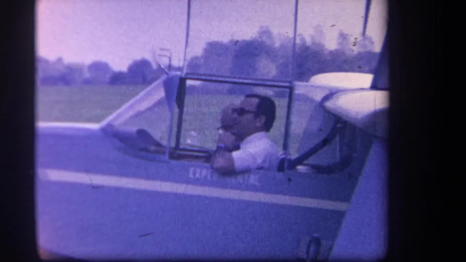 Close 1959 home-movie view of the pilot adjusting or checking something near the cockpit of the experimental glider.