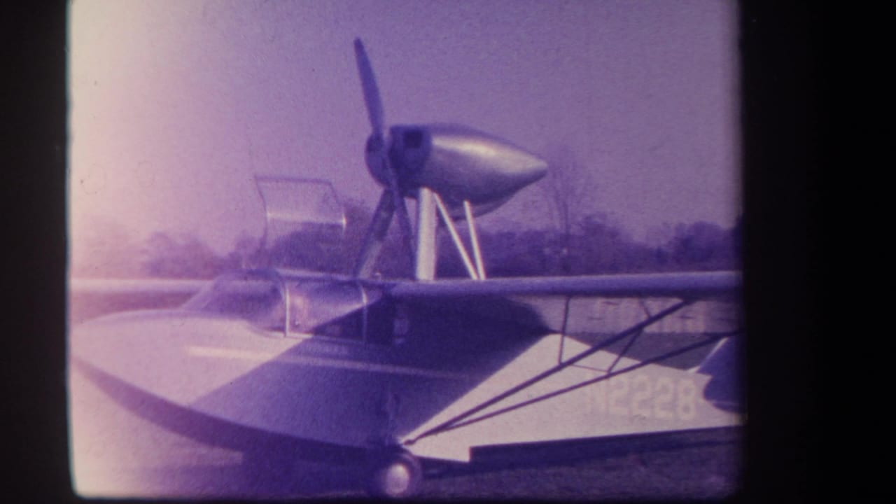 Side view of an amphibious aircraft with propeller, high wing, and fuselage marking.
