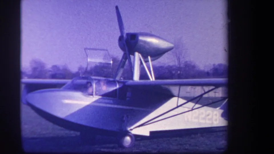 1959 California 8mm frame showing the side of amphibious aircraft N2228, with canopy, wing struts, and rear propeller structure.
