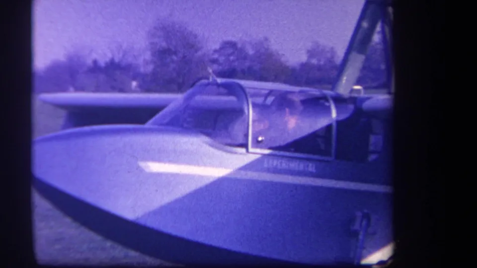 Purple-tinted 8mm frame showing the nose and cockpit of a 1959 experimental airplane in Yucaipa, California.