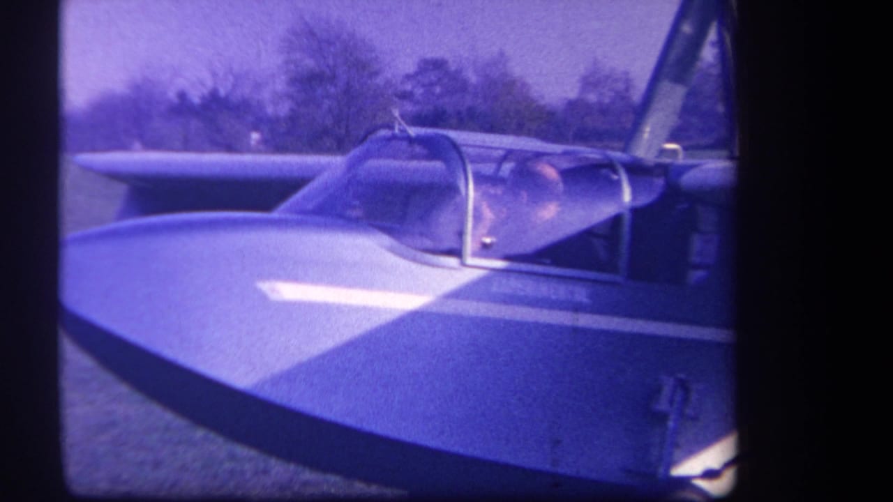 1959 Yucaipa-area 8mm frame showing a close view of a small experimental aircraft with a pilot seated under a transparent canopy.