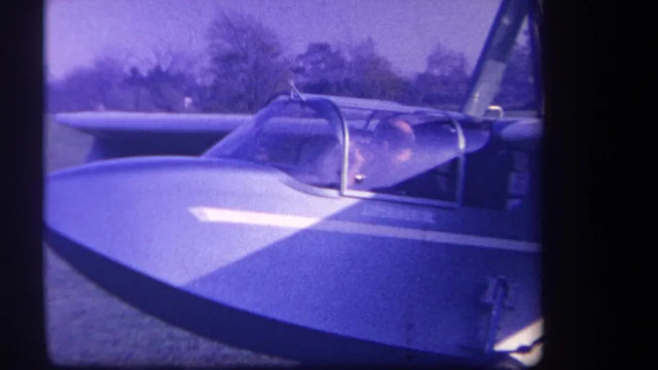 1959 Yucaipa-area 8mm frame showing a close view of a small experimental aircraft with a pilot seated under a transparent canopy.