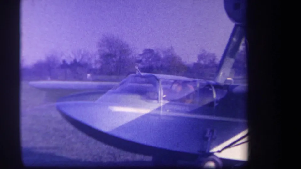 1959 Yucaipa-area home-movie view of the aircraft nose, canopy, and seated person on a grass airfield.