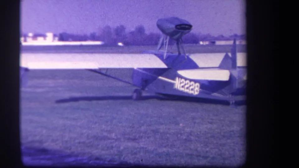 1959 Yucaipa-area frame showing the small airplane marked N2228 from the side on a mowed grass field.