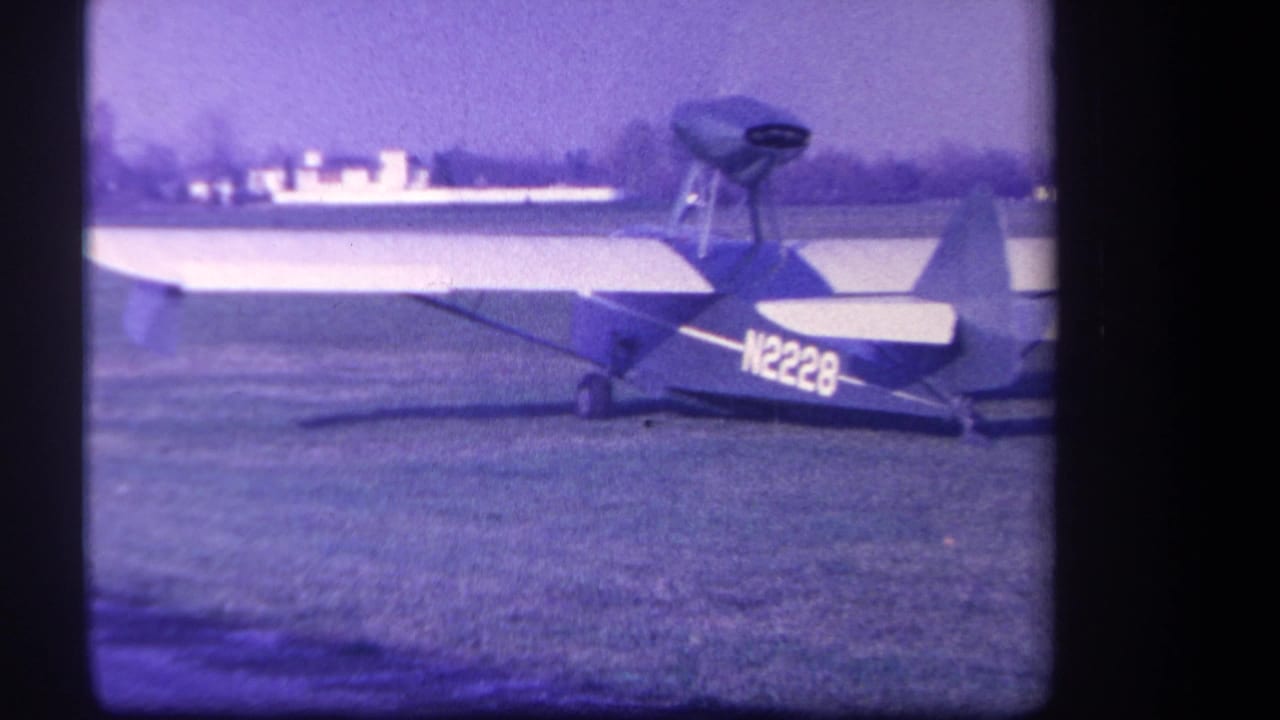 1959 Yucaipa-area home-movie frame showing a small single-engine aircraft on grass with its registration marking visible.